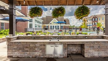 A patio with a grill and a view of a residential area.